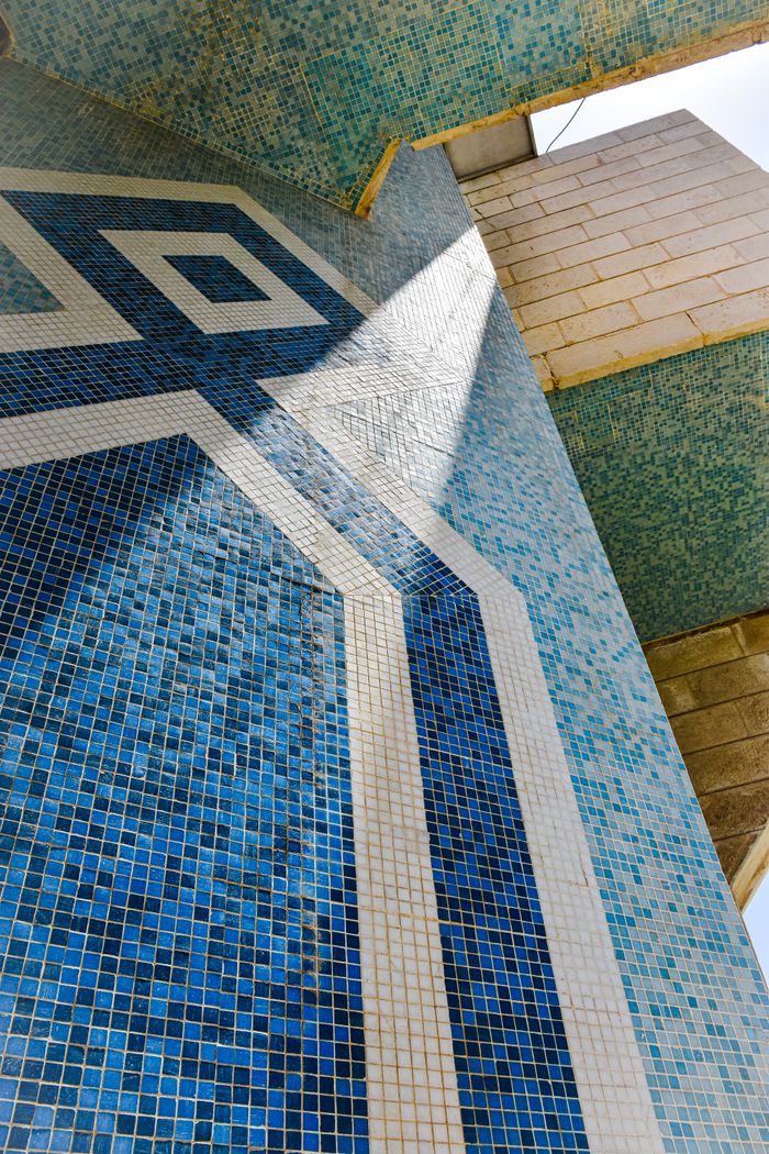 Blue and white geometric mosaic facade in sunlight showcases modern architectural design.